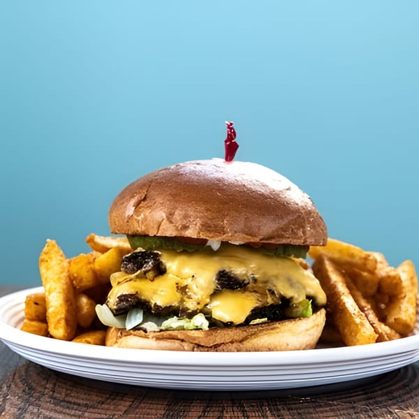 A Holy Bowly burger with melted cheese, lettuce, and pickles, served with golden fries.